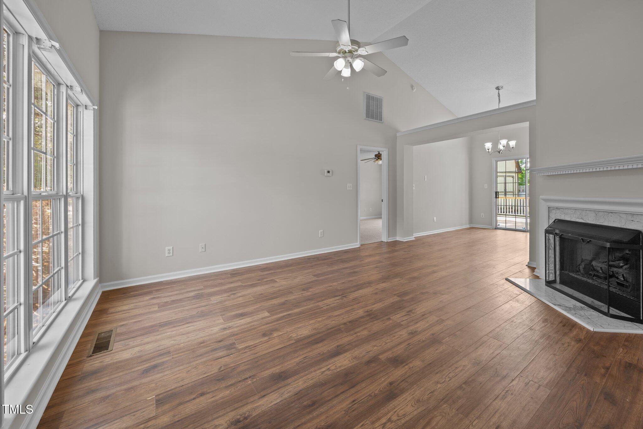 408 Flagg Road Holly Springs, NC 27540 - Photo 7 of 32 an empty room with wooden floor fireplace fan and windows