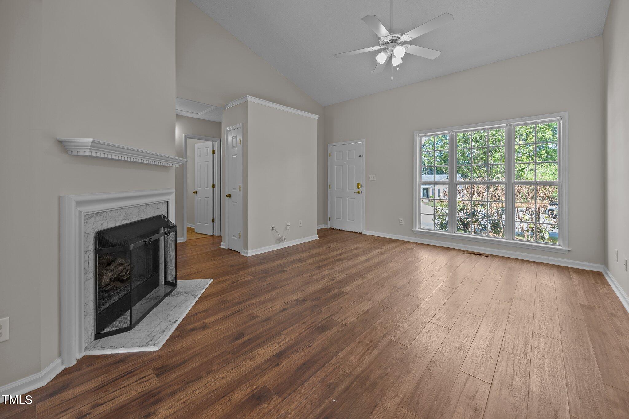 408 Flagg Road Holly Springs, NC 27540 - Photo 8 of 32 an empty room with wooden floor a fireplace and windows