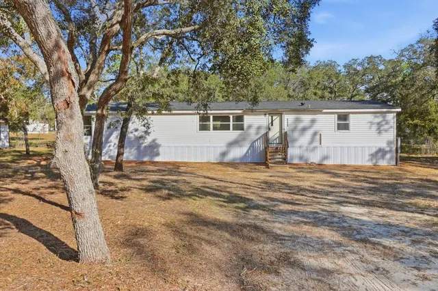 a backyard of a house with wooden fence and large trees