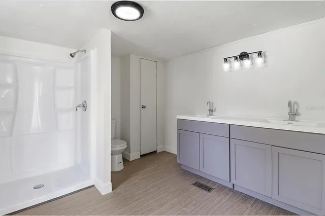 a bathroom with a double vanity sink toilet and shower