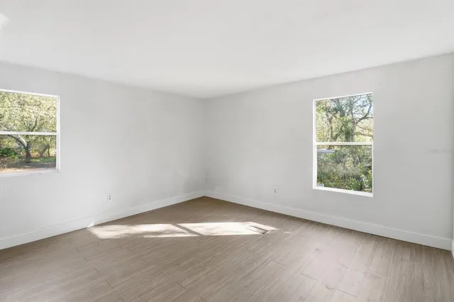 an empty room with wooden floor and windows