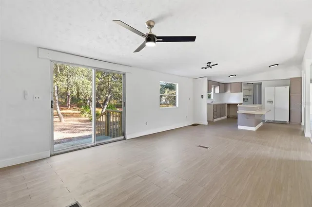 a view of a livingroom with wooden floor a ceiling fan and windows