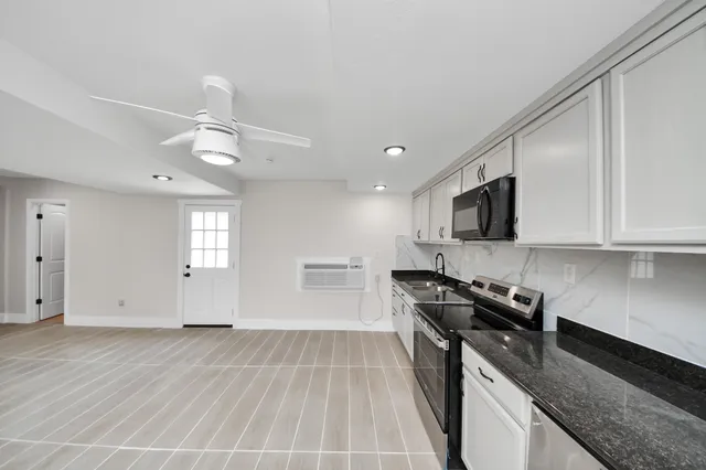 a kitchen with stainless steel appliances granite countertop a sink dishwasher stove and microwave with wooden floor