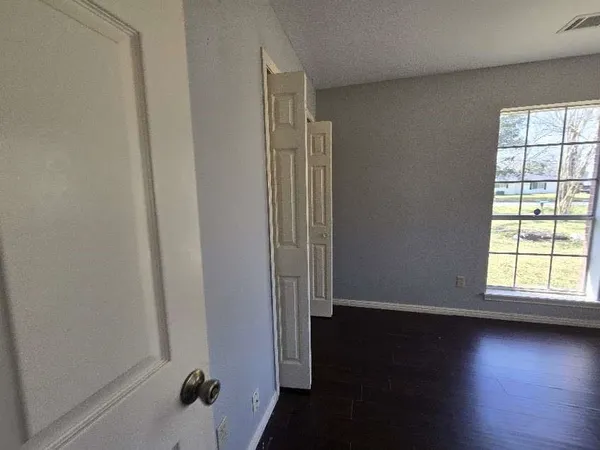 an empty room with wooden floor and windows