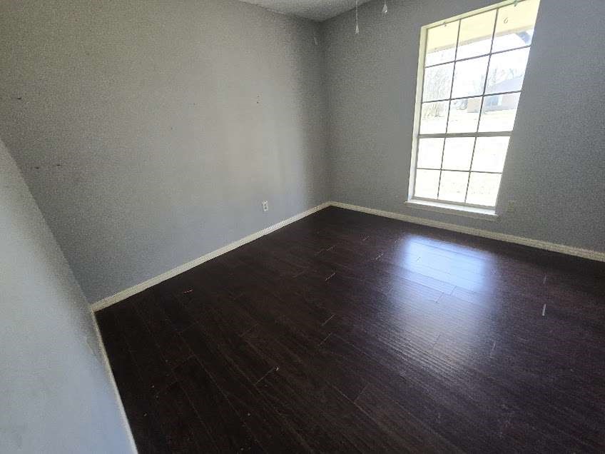 509 Bobcat Lane Daisetta, TX 77533 - Photo 12 of 13 an empty room with wooden floor and windows
