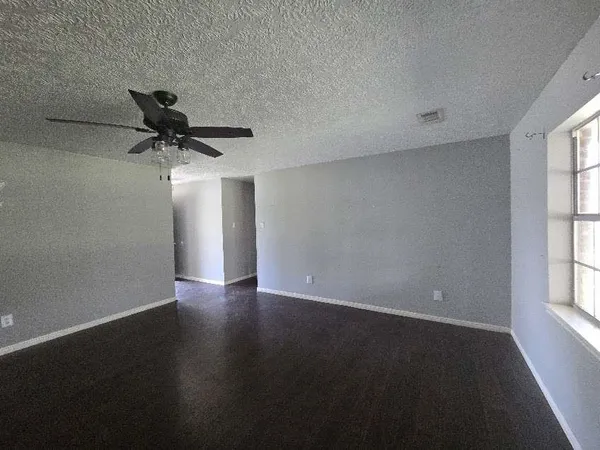 an empty room with a window and a ceiling fan