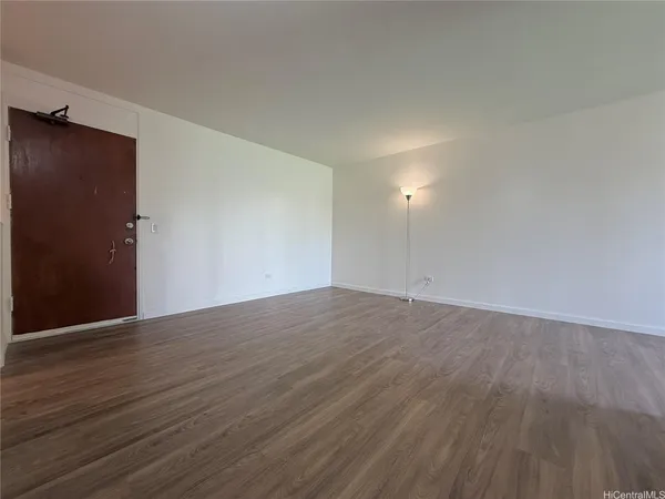 a view of an empty room with wooden floor and closet