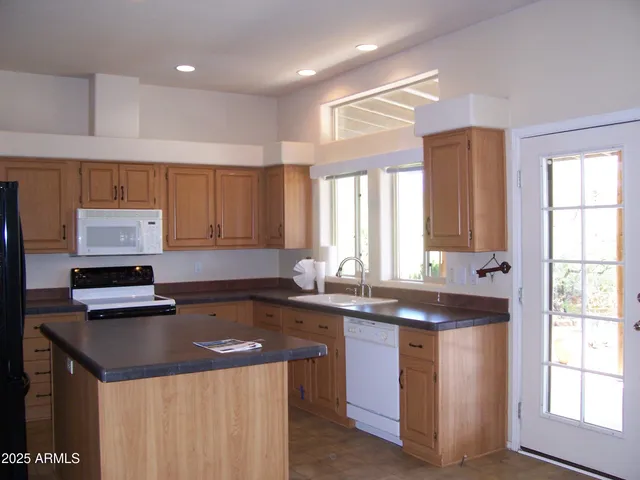 a kitchen with kitchen island granite countertop a sink stove and cabinets