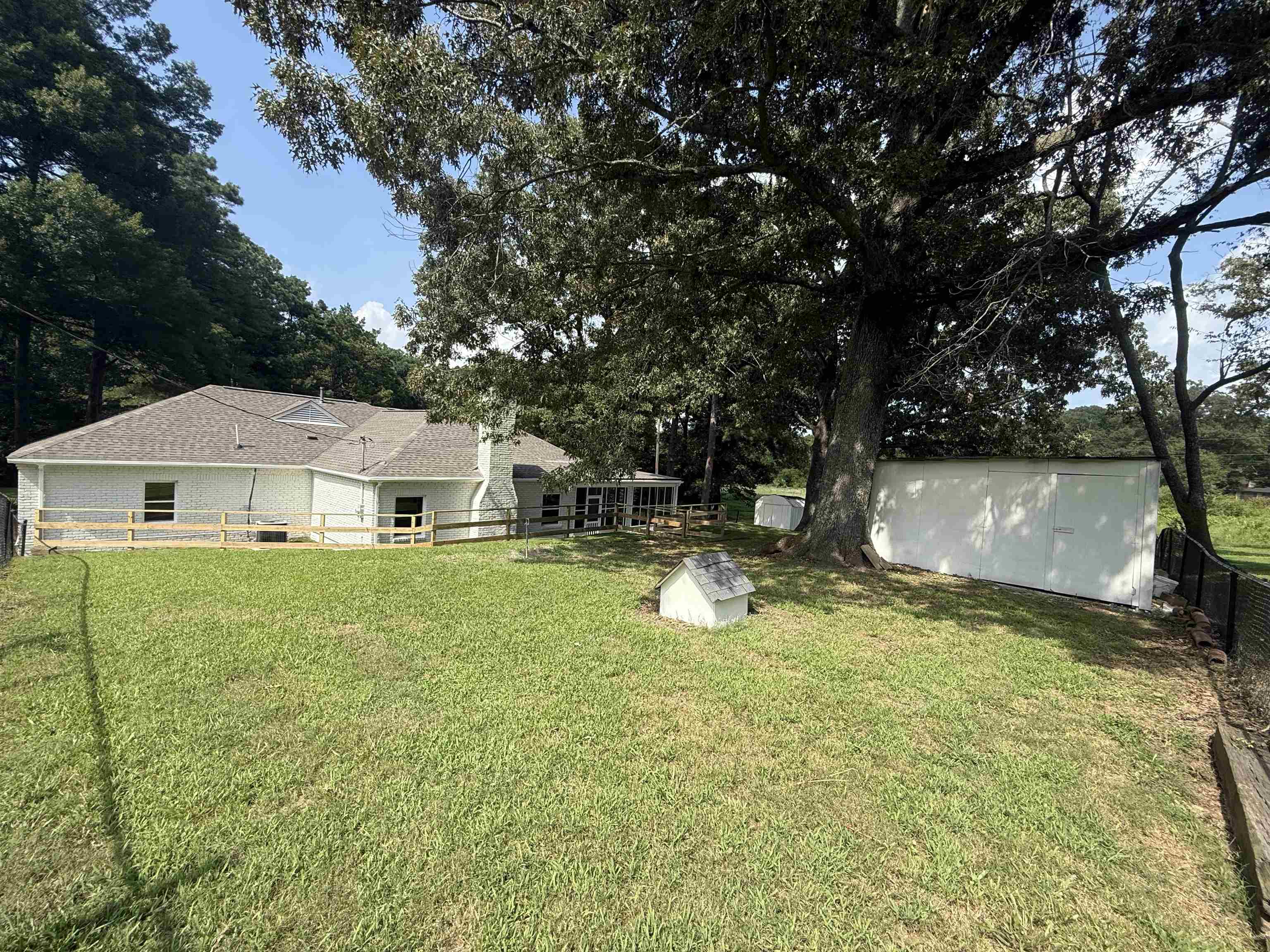 1835 Pleasant Grove Road Moscow, TN 38057 - Photo 31 of 34 Expansive grassy yard featuring a large mature tree, a white storage shed, and a privacy fence