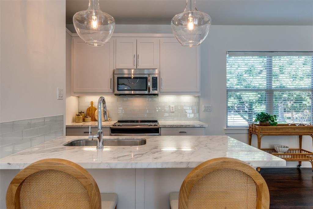 5830 Oram Street, Unit 5 Dallas, TX 75206 - Photo 13 of 18 a kitchen with kitchen island granite countertop a sink a stove and a chandelier