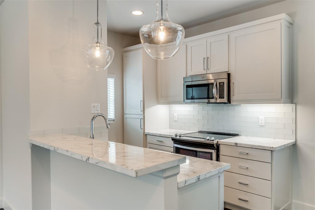 a kitchen with stainless steel appliances a stove a microwave and a sink with wooden floor