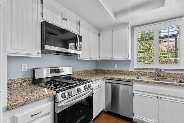 a kitchen with stainless steel appliances granite countertop white cabinets granite counter tops and a wooden floors
