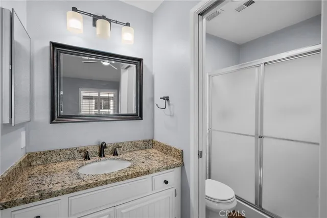 a bathroom with a granite countertop sink toilet and mirror