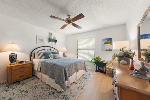 a bedroom with a bed a large window and potted plant on the dresser