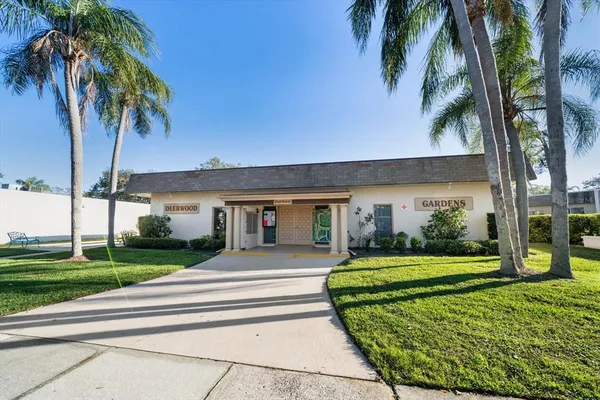 a front view of a house with a garden and trees