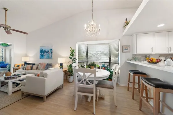 a living room with furniture kitchen view and a chandelier