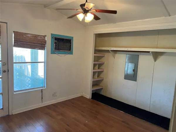a view of empty room with wooden floor and fan