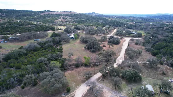 an aerial view of residential houses with outdoor space and trees