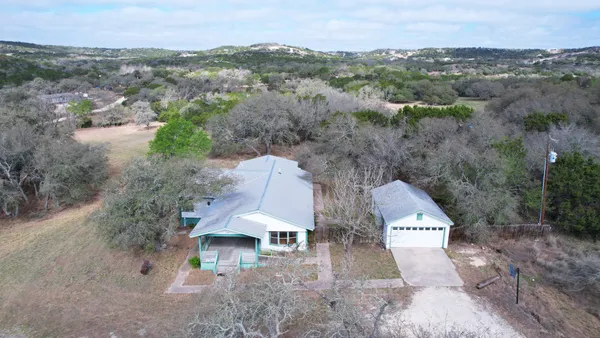 an aerial view of a house with a yard and mountain view in back