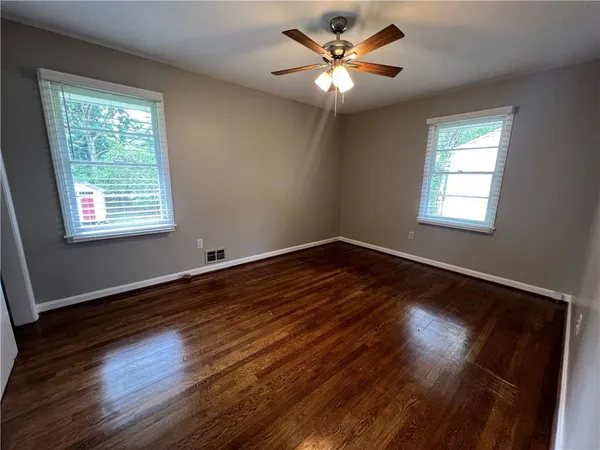 a view of an empty room with wooden floor and a window