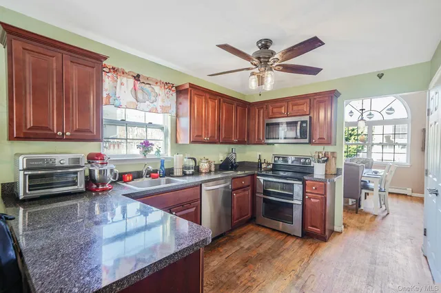 a kitchen with stainless steel appliances granite countertop a stove top oven a sink dishwasher and cabinets with wooden floor