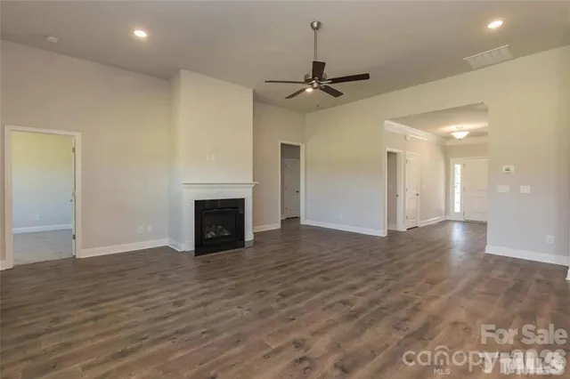 a view of an empty room with wooden floor fireplace and a window