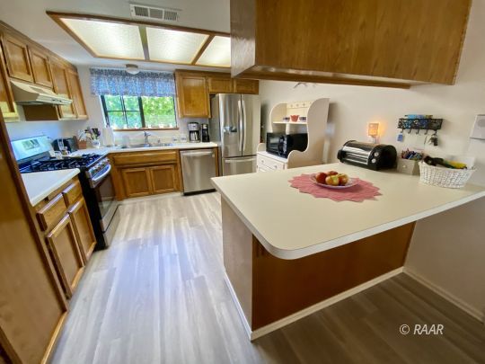 812 Charles Court Ridgecrest, CA 93555 - Photo 20 of 32 a kitchen with kitchen island a stove a sink a refrigerator cabinets and wooden floor