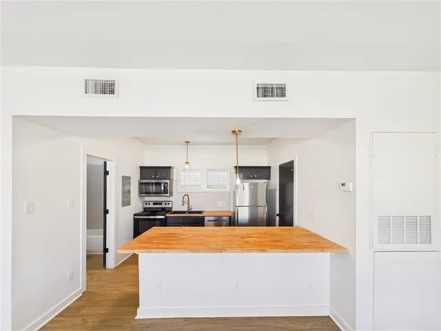 a kitchen with stainless steel appliances kitchen island granite countertop a refrigerator stove and sink