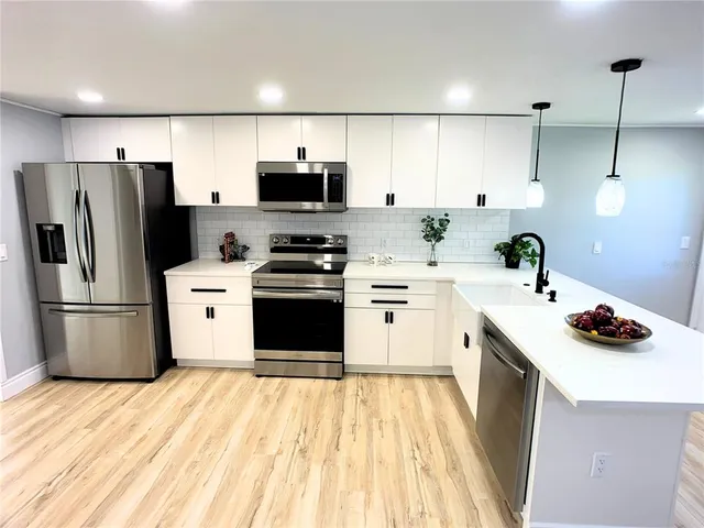 a kitchen with stainless steel appliances a stove a sink a refrigerator and cabinets