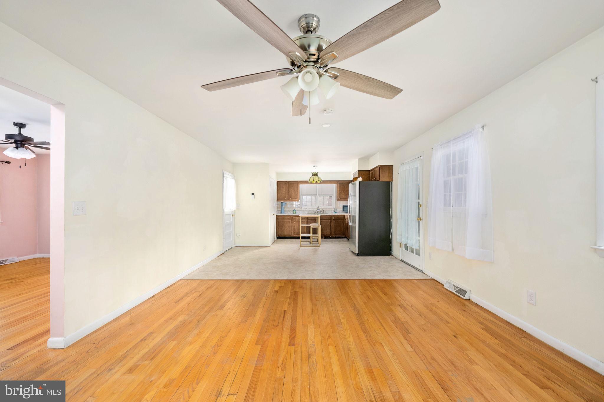 128 11th Street Colonial Beach, VA 22443 - Photo 18 of 58 a big room with wooden floor a ceiling fan and kitchen space