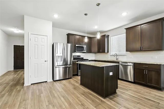a kitchen with stainless steel appliances granite countertop a refrigerator and a stove top oven