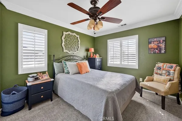 a bedroom with a bed a flat screen tv and windows