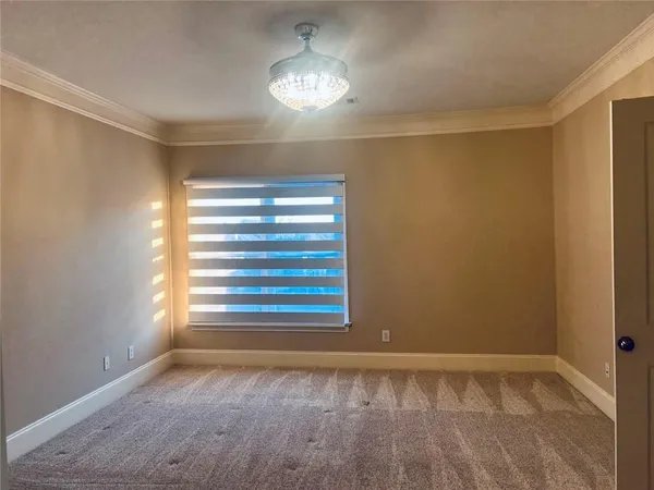 a view of an empty room with window and chandelier fan