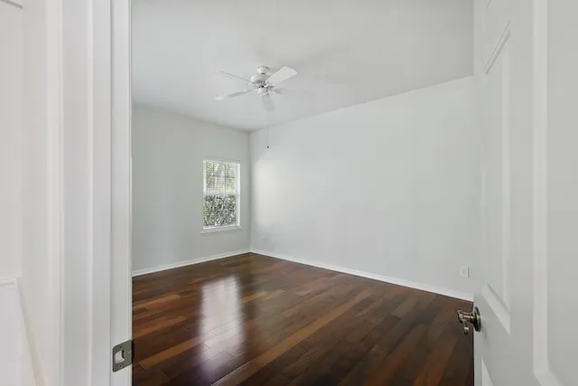 an empty room with wooden floor closet and fan