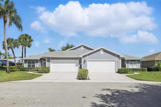 a front view of a house with a garden and trees