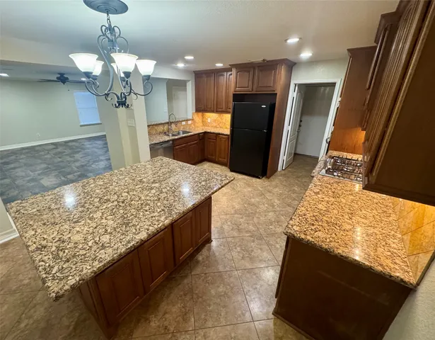 a kitchen with kitchen island granite countertop wooden cabinets and a counter top space