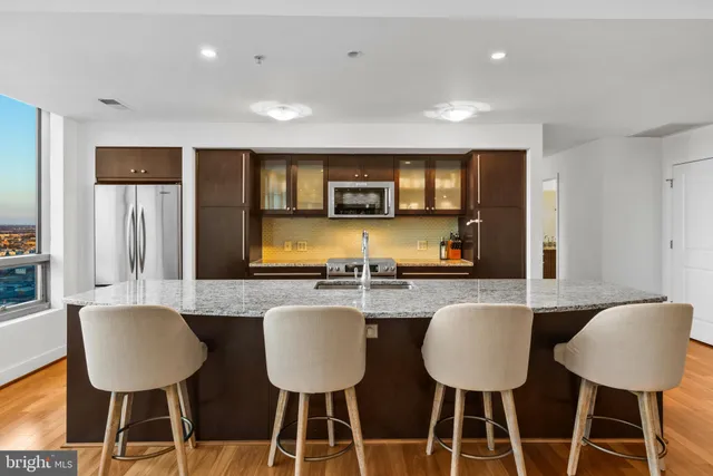 a kitchen with stainless steel appliances granite countertop a table chairs and a refrigerator