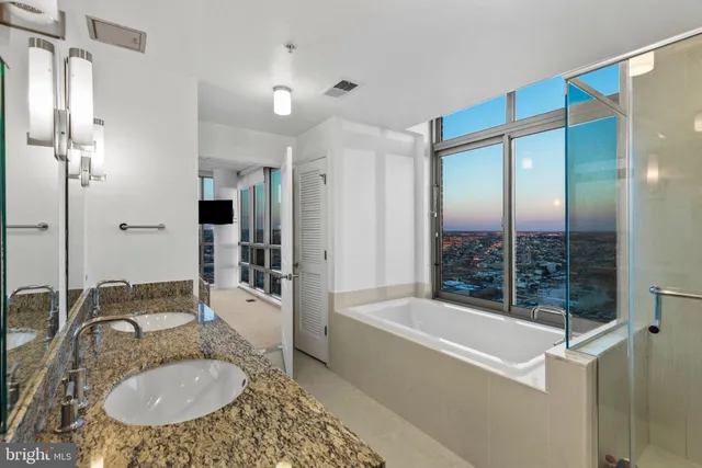 a bathroom with a granite countertop tub sink and mirror