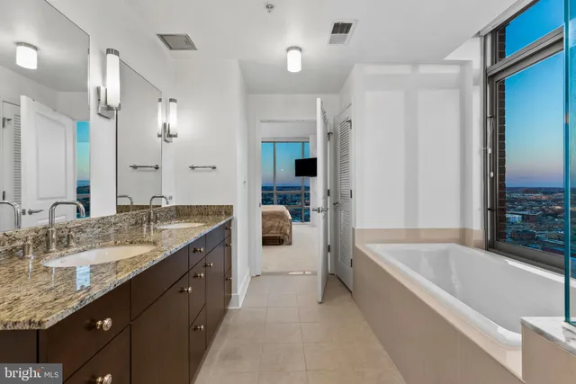 a spacious bathroom with a granite countertop tub double vanity sink and a large mirror