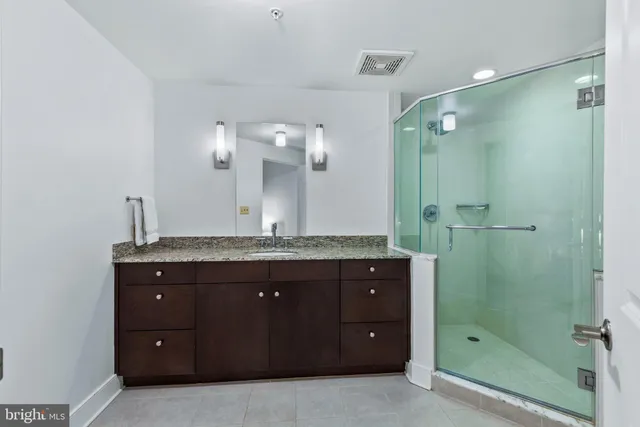 a bathroom with a granite countertop sink mirror and shower