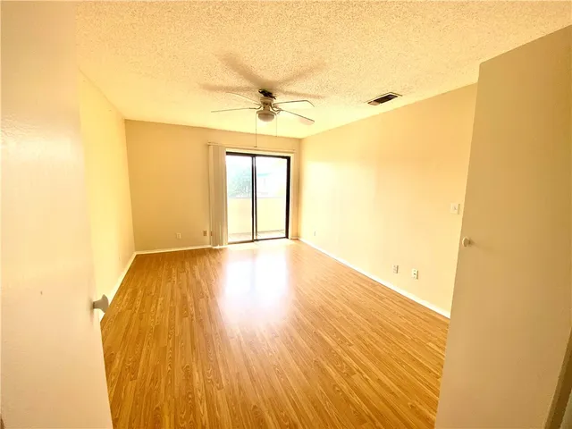 a view of a room with wooden floor and a ceiling fan