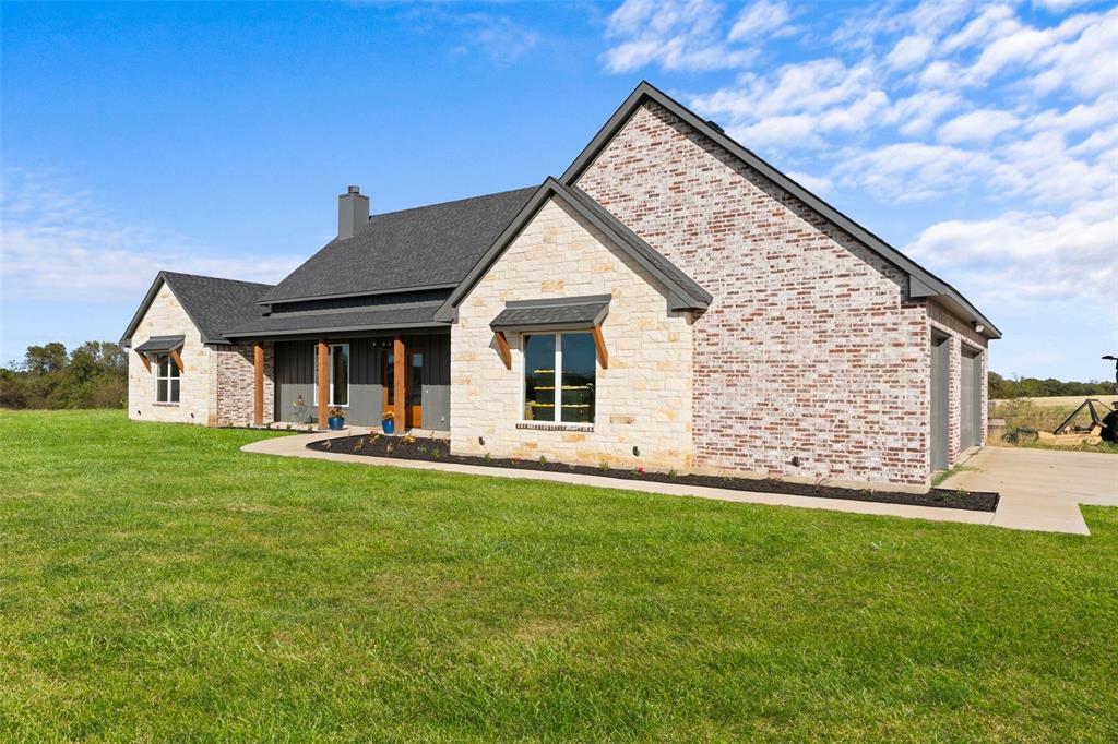 4411 Fm 751 Wills Point Wills Point, TX 75169 - Photo 5 of 40 Exterior featuring a blend of light-colored brick and stone, a dark gray shingle roof, and a covered porch with natural wood posts