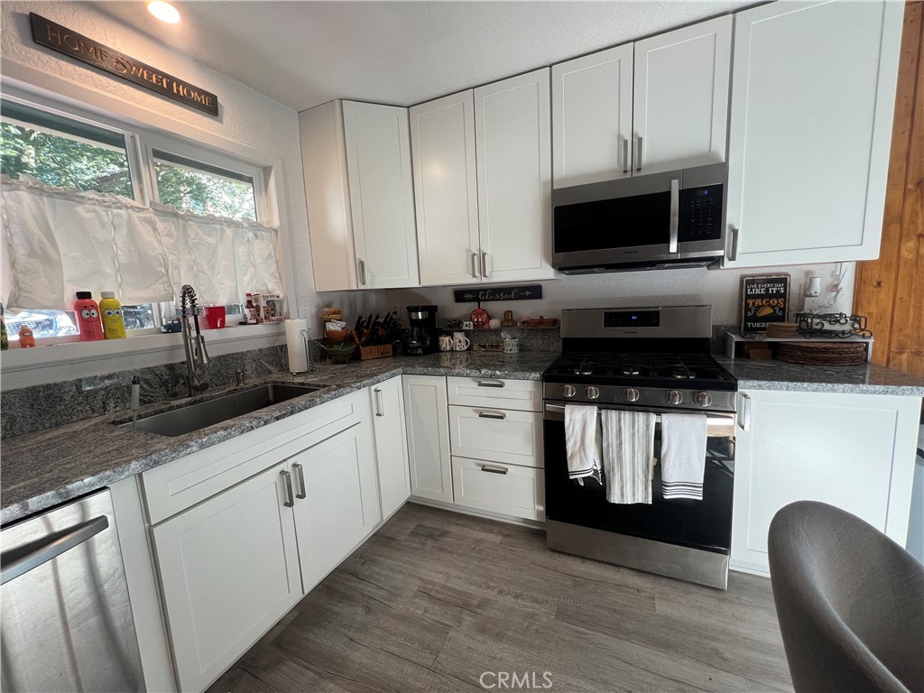23857 Zuger Drive Crestline, CA 92325 - Photo 4 of 29 a kitchen with stainless steel appliances a stove a sink and white cabinets