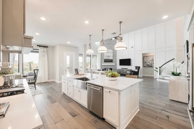 a large white kitchen with a large center island and stainless steel appliances