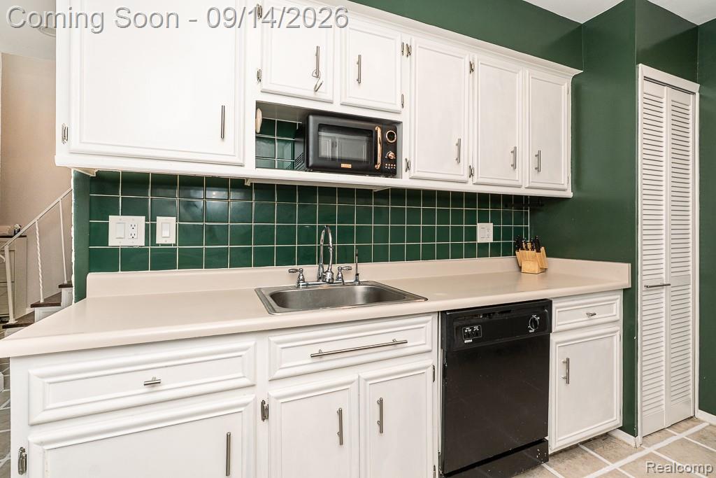 104 Manor Way Rochester, MI 48309 - Photo 22 of 53 White cabinetry with silver-tone hardware, green tile backsplash, stainless steel sink with chrome faucet, black dishwasher, and laminate countertops