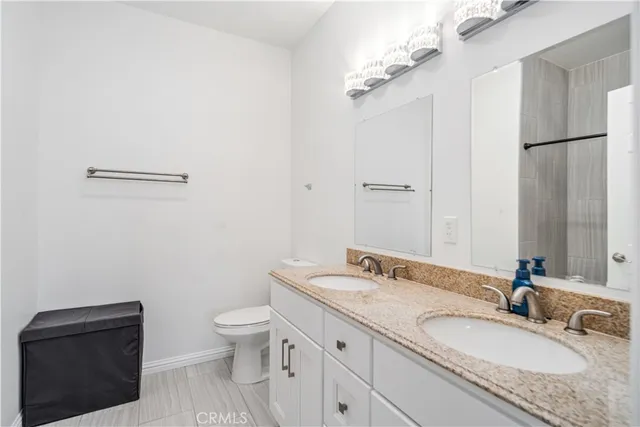 a bathroom with a granite countertop sink toilet and a mirror