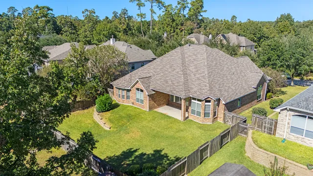 an aerial view of a house with swimming pool and large trees