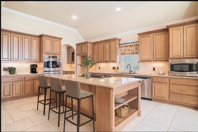 a kitchen with stainless steel appliances granite countertop a stove top oven a sink dishwasher and a refrigerator with wooden cabinets