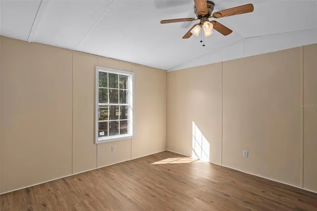 a view of an empty room with window and wooden floor