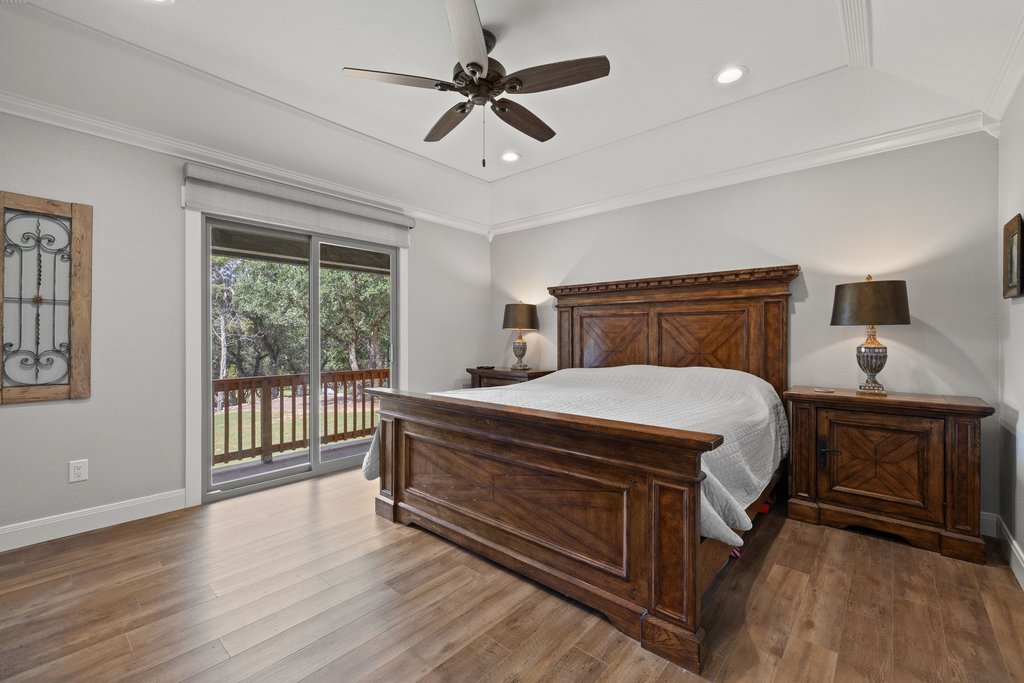 23644 Nameless Road Leander, TX 78641 - Photo 15 of 40 A spacious bedroom with rich wood flooring and a private outdoor deck offers a tranquil retreat.